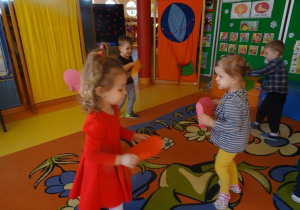 Dzieci tańczą z papierowymi sercami.
